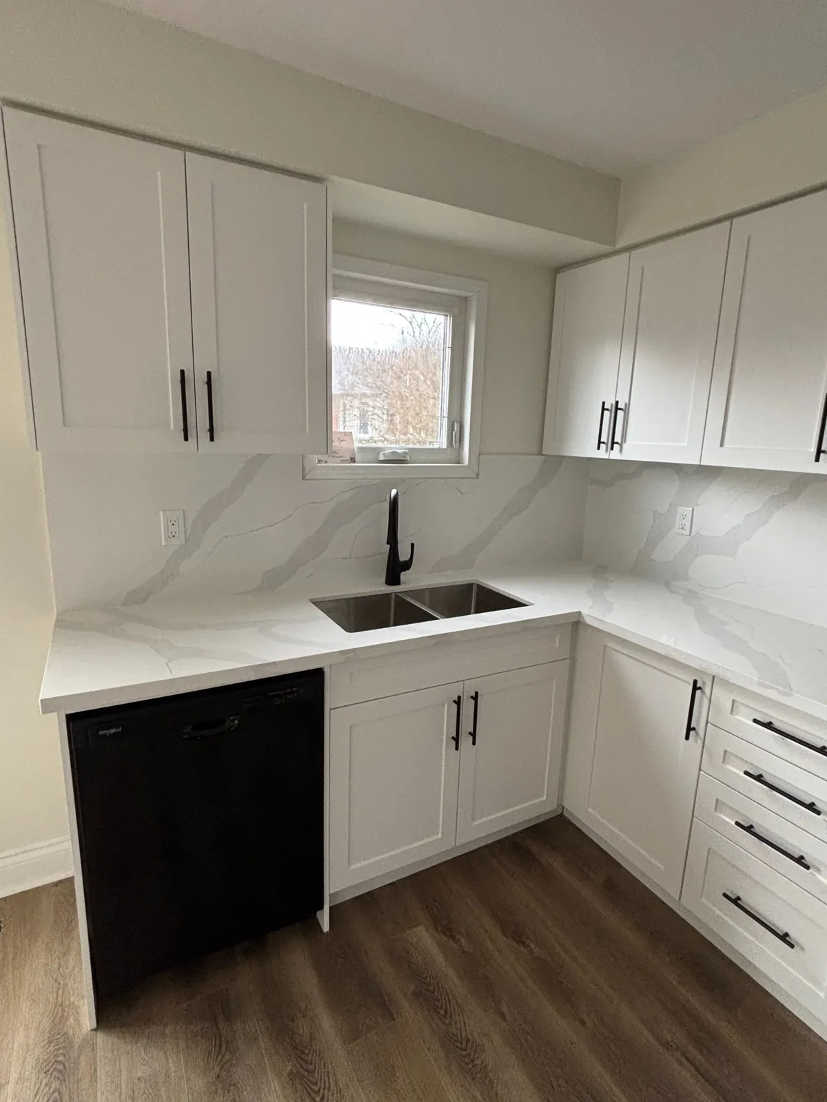 Compact Kitchen Remodel – Bowmanville Project Compact kitchen renovation with white cabinets, black appliances, and marble backsplash