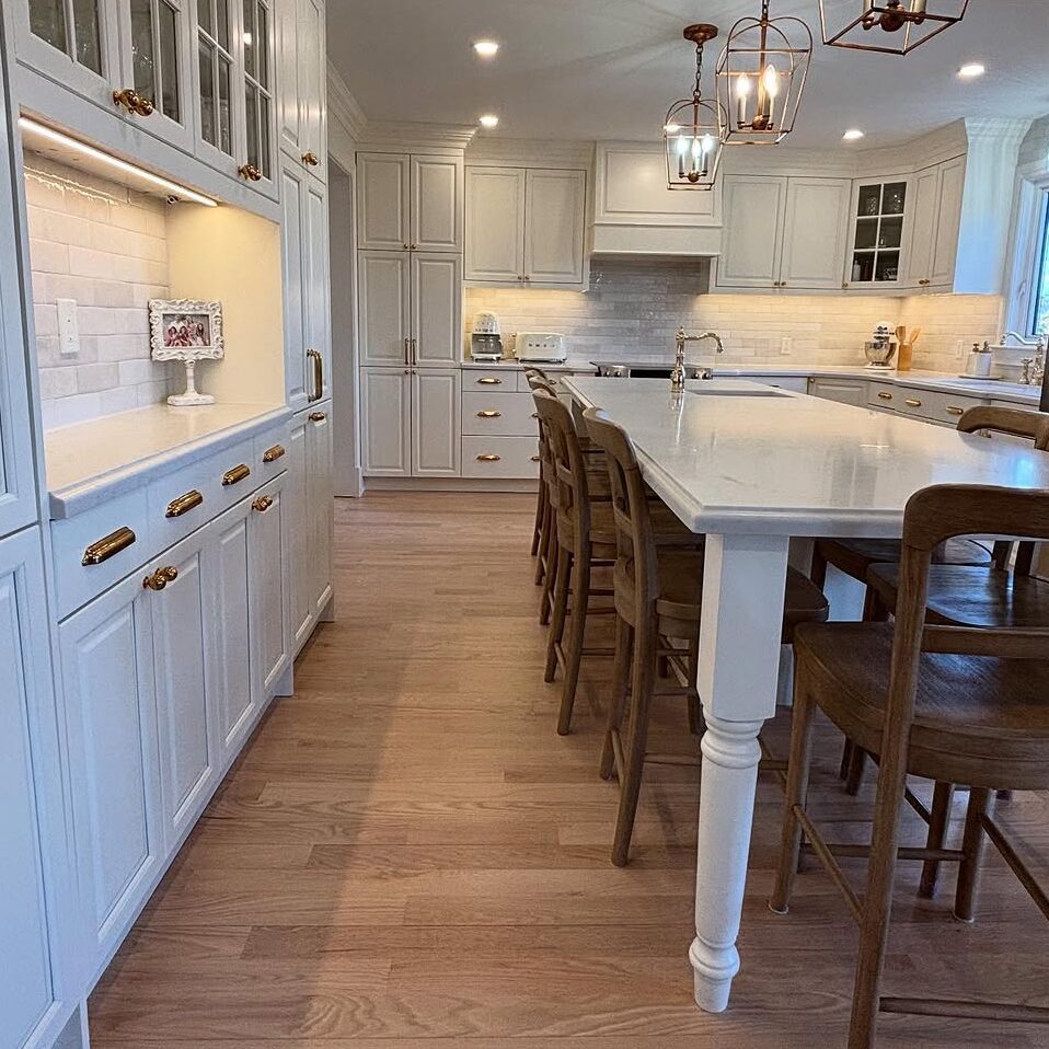 Bright White Kitchen Remodel – Courtice Bright white kitchen renovation in Courtice with gold hardware and wood stools around large island