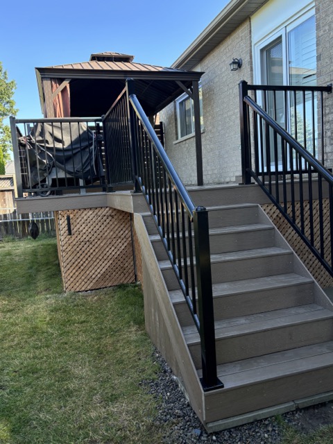 Durham Region Composite Deck by Wilworks Renovations Composite deck with black aluminum railings and staircase leading to a backyard gazebo in Durham Region, built by Wilworks Renovations.